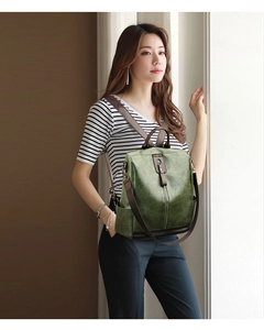 Detail view of a dark green faux leather backpack with contrasting brown straps on a model