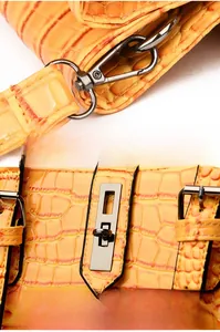 Détail du sac orange en cuir crocodile avec fermoir en métal argenté et crochets