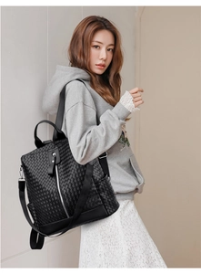 Side view of model wearing black woven leather backpack with silver vertical zipper