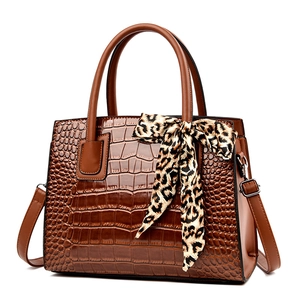 Sac à main marron motif crocodile avec foulard léopard sur fond blanc pur