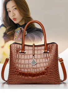 Detailed view of dark brown crocodile texture surface and silver pendant on handbag
