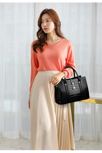 Detail of black crocodile embossed tote bag with gold metal hardware and top handle