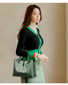 Detail of dark green handbag with glossy stone texture and elegant metal pendant charm