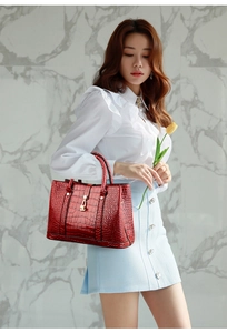 Close-up of wine red crocodile embossed texture and golden metal lock on handbag