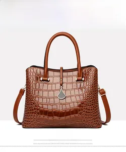 Front view of yellow-brown crocodile embossed leather tote bag with metal pendant charm