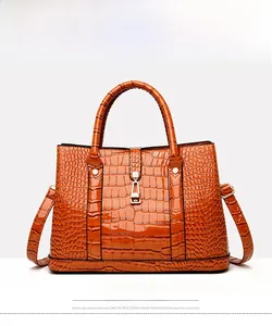 Macro detail of brown crocodile pattern embossed handbag with metallic buckle and strap