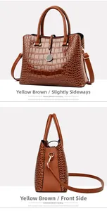 Detail view of brown crocodile pattern handbag with dual handles and golden pendant