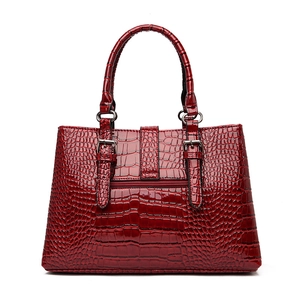 Sac à main bordeaux avec motif crocodile effet verni brillant et boucles métalliques sur blanc