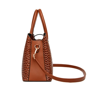 Brown crocodile embossed handbag with gold hardware and shoulder strap in side view