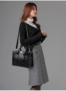 Detail of black crocodile texture tote bag with gold hardware and removable strap