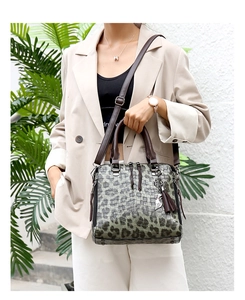 Makroaufnahme der dunkelgrünen Kroko-Tasche mit Quaste und silbernem Katzen-Anhänger