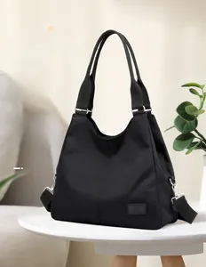 Detail of black nylon tote bag featuring durable handles and adjustable wide shoulder strap