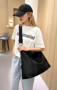 Dettaglio di una borsa a tracolla in nylon nero con tracolla larga su un modello