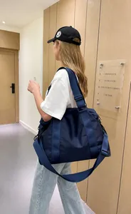 Vista laterale di una borsa da viaggio grande in nylon blu scuro indossata da una modella