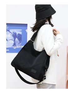 Close-up of black nylon tote bag with adjustable wide shoulder strap and brand logo