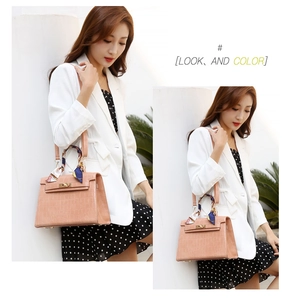 Detail of pink crocodile-embossed handbag with gold twist lock and scarf-wrapped handle
