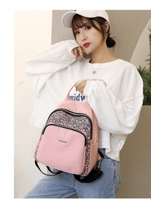 Detail of pink nylon backpack featuring geometric patterns and durable metal zippers