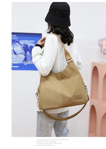 Detail of khaki nylon tote bag showing leather logo patch and detachable shoulder strap