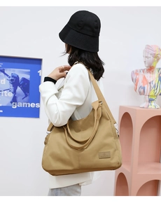 Close-up of khaki nylon tote bag with wide straps and brand logo on a stylish model