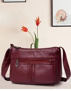 Dettaglio borsa a tracolla rosso vino in morbida pelle con texture intrecciata e multi-zip