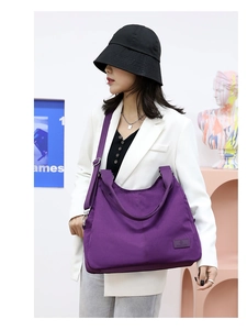 Detail of purple nylon tote bag featuring durable fabric handles and brand logo patch