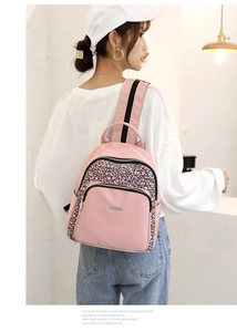 Detail view of pink Oxford fabric backpack showing geometric pattern and logo on model