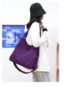 Detail of purple nylon shoulder bag showing adjustable strap and brand patch on model