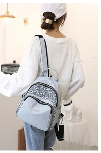 Rear view of model wearing a light blue-gray Oxford backpack with geometric print pattern