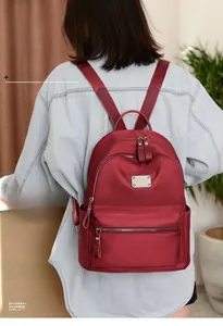 Close-up of wine red oxford cloth backpack featuring silver zippers and side pockets
