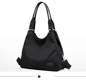 Detailed side view of black nylon tote bag showing metallic buckles and textured fabric