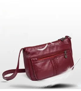Dettaglio della borsa a tracolla bordeaux con zip multiple e design con trama intrecciata
