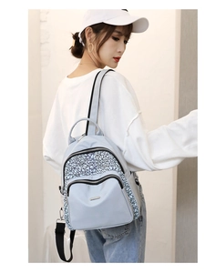 Detailed view of oxford backpack with patterned zip pockets and metal logo plate