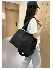 Vista laterale di una grande borsa tote in nylon nero indossata da una modella per viaggi
