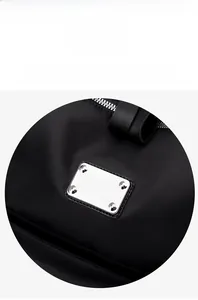 Detail of black oxford fabric backpack featuring silver rectangular hardware and metal zipper