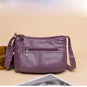 Dettaglio borsa a tracolla viola in pelle morbida con tasche a zip e trama intrecciata
