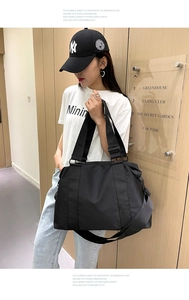 Dettaglio della borsa da viaggio in nylon nero con tracolla regolabile e manici rinforzati