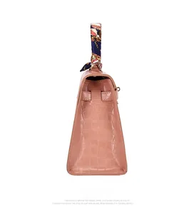 Pink embossed crocodile texture handbag side view with decorative handle scarf