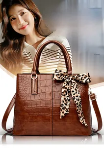 Close-up of deep brown crocodile pattern leather handbag with leopard print scarf detail