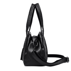 Black pebbled leather tote bag with braided handles and decorative tassels for women
