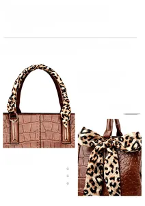 Close-up of brown crocodile pattern handbag with leopard print ribbon and gold hardware