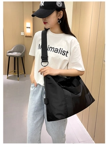 Grande borsa a tracolla in nylon nero con tracolla regolabile indossata da modella