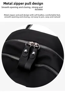 Close-up of smooth dual metal zippers and leather pullers on black nylon backpack