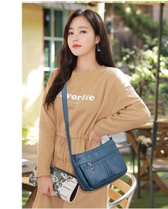Dettaglio della borsa a tracolla blu scuro con texture in pelle morbida e tasche multiple con zip