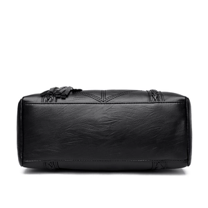 Black leather tote bag for women featuring textured grain and decorative tassel detail