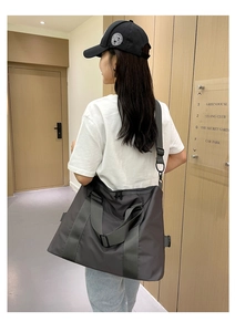 Borsa da viaggio in nylon grigio scuro con tracolla regolabile indossata da modella