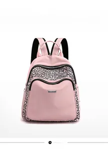 Detailed front view of pink nylon backpack featuring black geometric patterns and twin front pockets