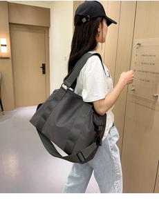 Dettaglio borsa da viaggio in nylon grigio scuro con tracolla regolabile e fibbia laterale