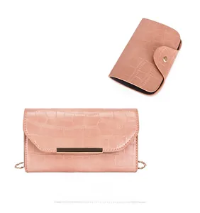 Detail of pink crocodile pattern clutch with gold metal bar and fine chain strap