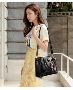 Detail of black crocodile texture handbag with leopard print scarf and shoulder strap