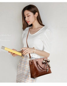 Detail of dark brown crocodile texture tote bag with leopard print silk scarf decoration